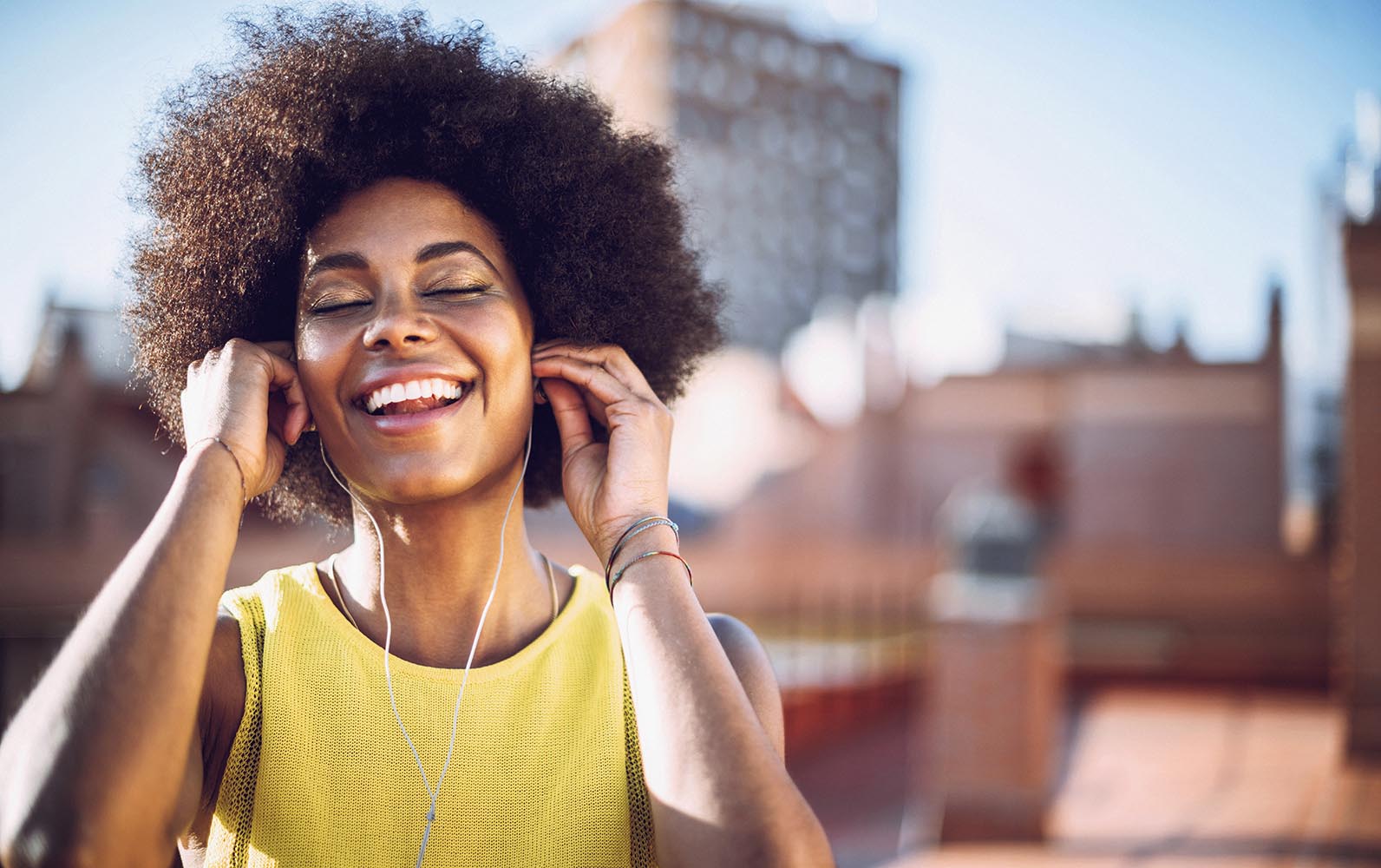 Young afro woman listen to music with headphones on the rooftop