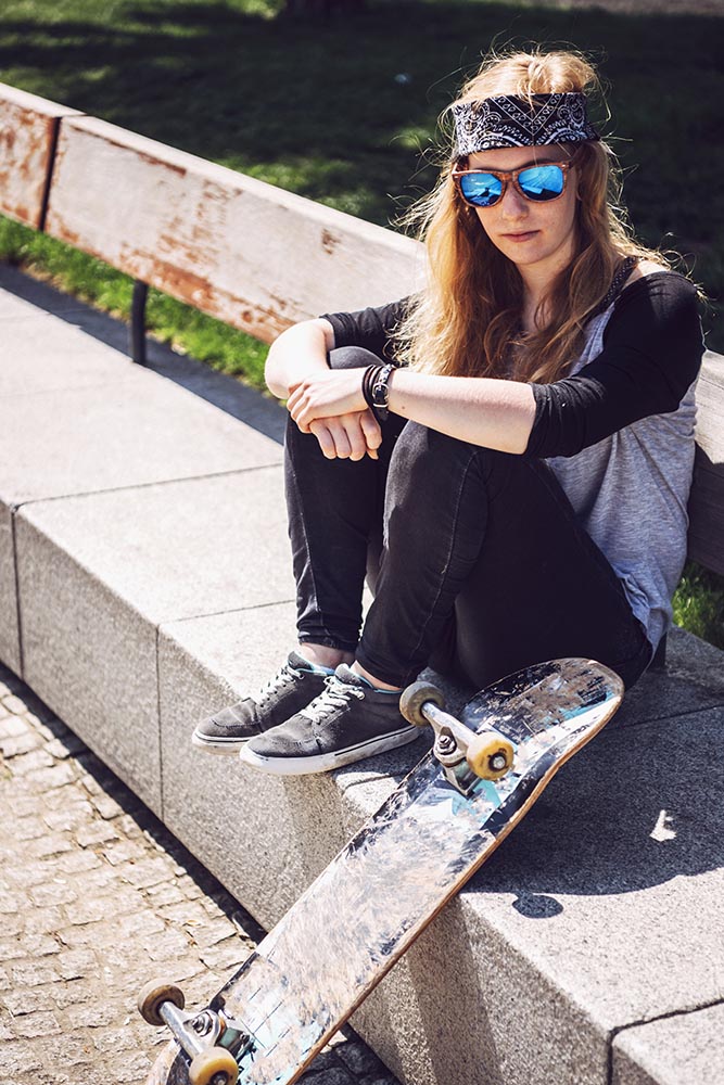 Woman skateboarder sitting in a park