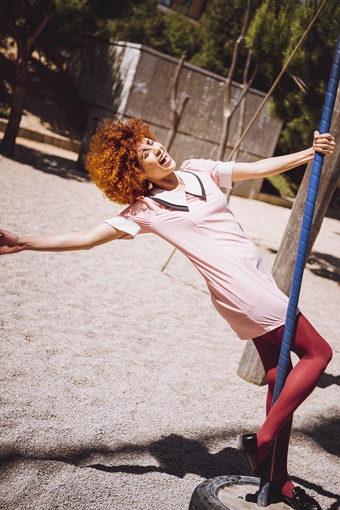 Trendy Young woman playing like a little girl on swings in a par