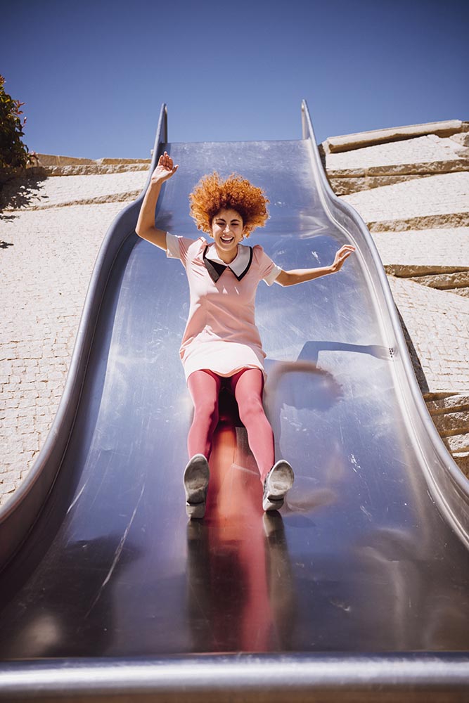 Young trendy woman playing in a park on slide