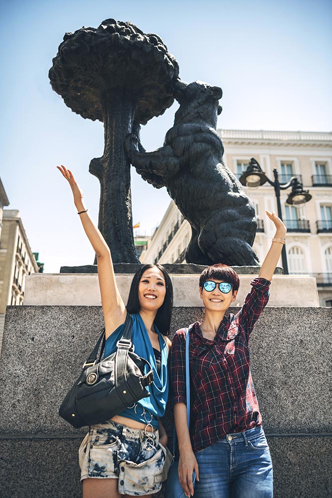 Cheerful friends traveling and posing near stature