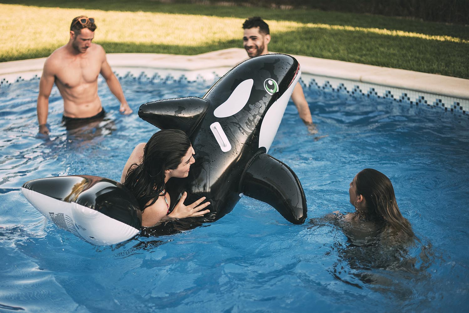 Friends swimming on inflatable toy in pool