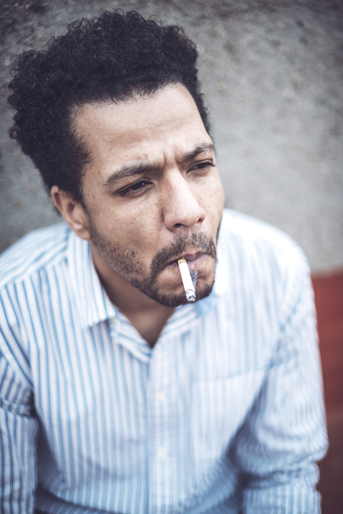 Confident attractive mulatto man smoking a cigarrette