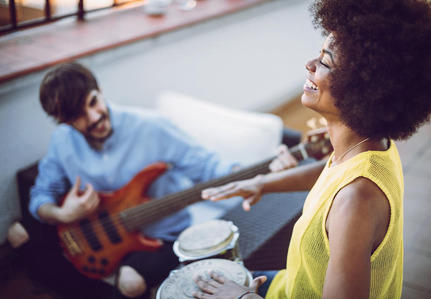 Multirracial young couple playing drums and a guitar