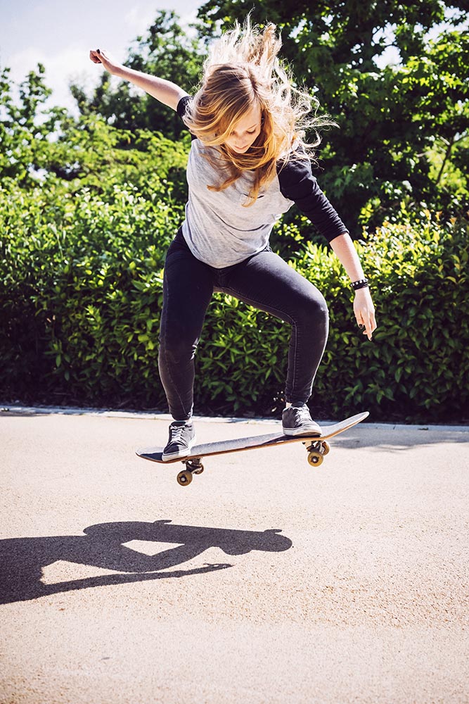 Skateboarder woman practicing ollie at park