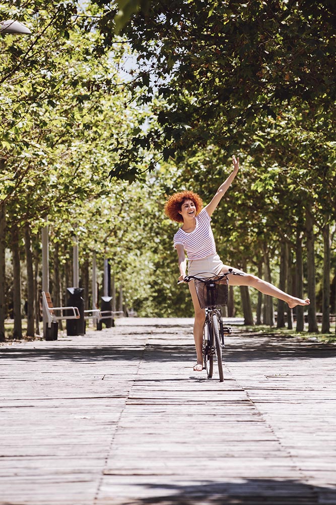 Cheerful girl riding a bike down the street