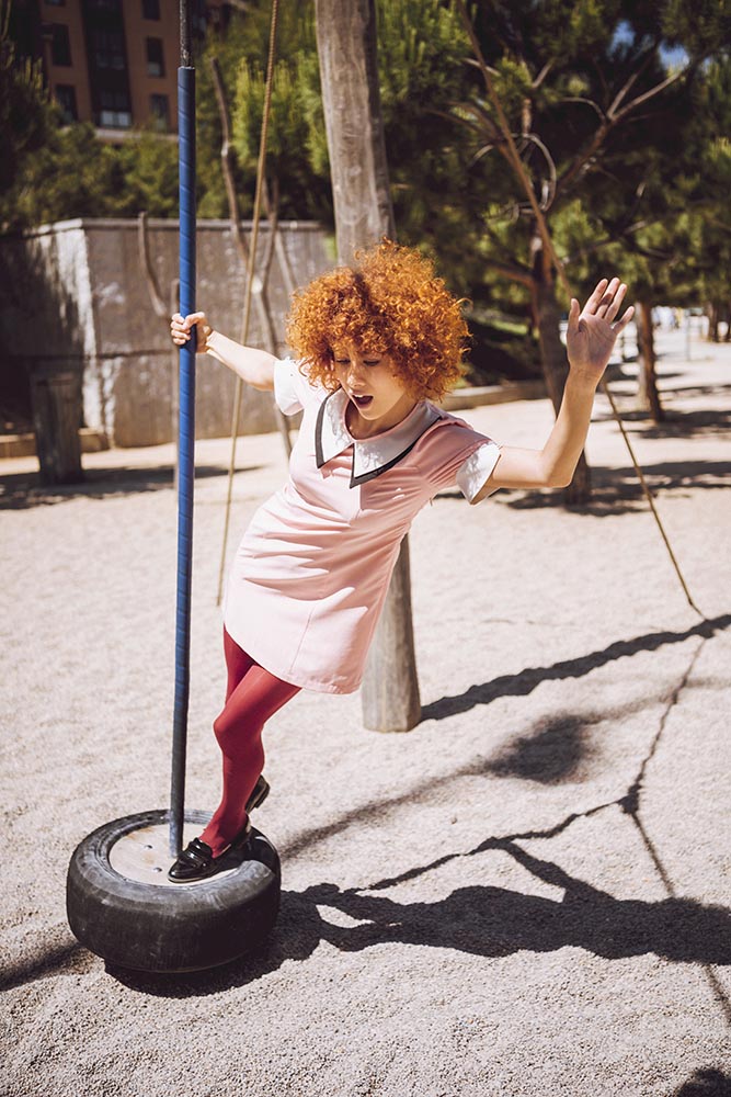 Trendy Young woman playing like a little girl on swings in a par