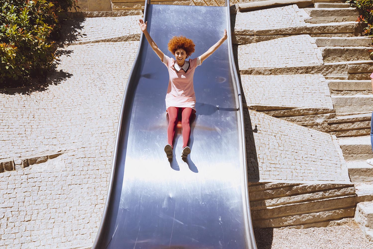 Young trendy woman playing in a park on slide