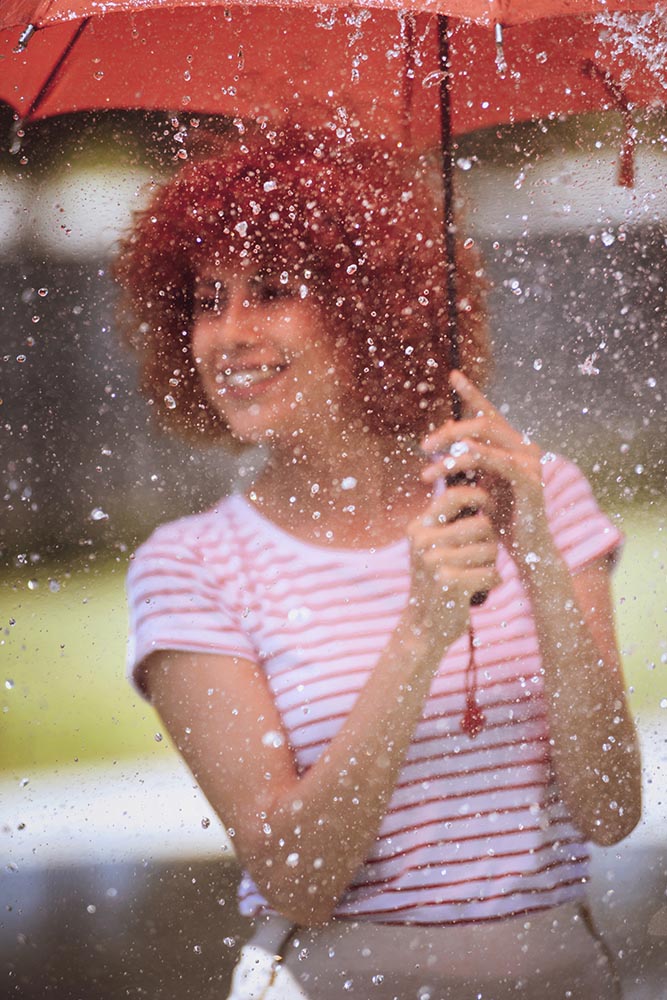 Young beautiful woman playing at outdoor water fountain with an