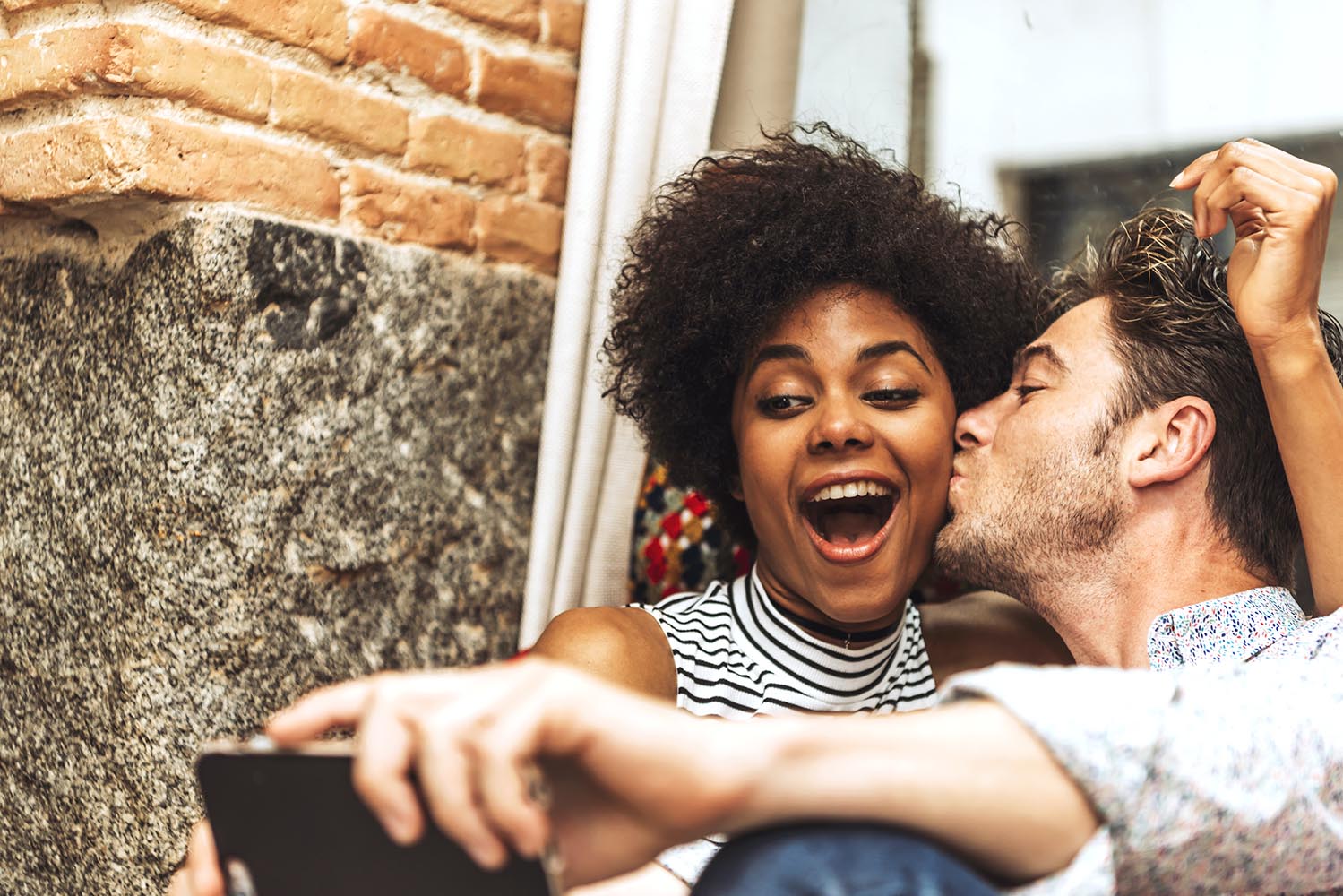 Laughing young couple kissing and taking selfie