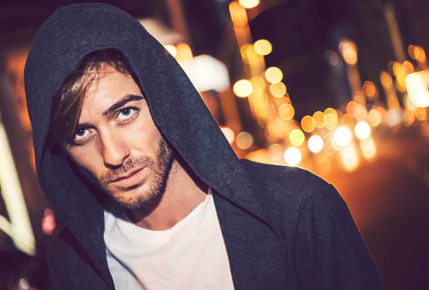 Attractive young caucasian man with hoodie in a city street at n