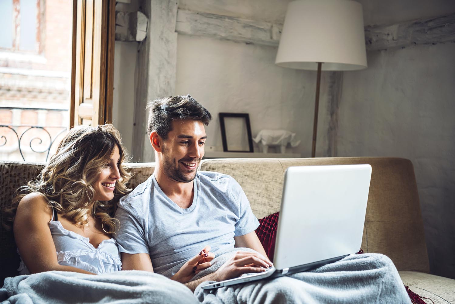 Young smiling couple on sofa with laptop