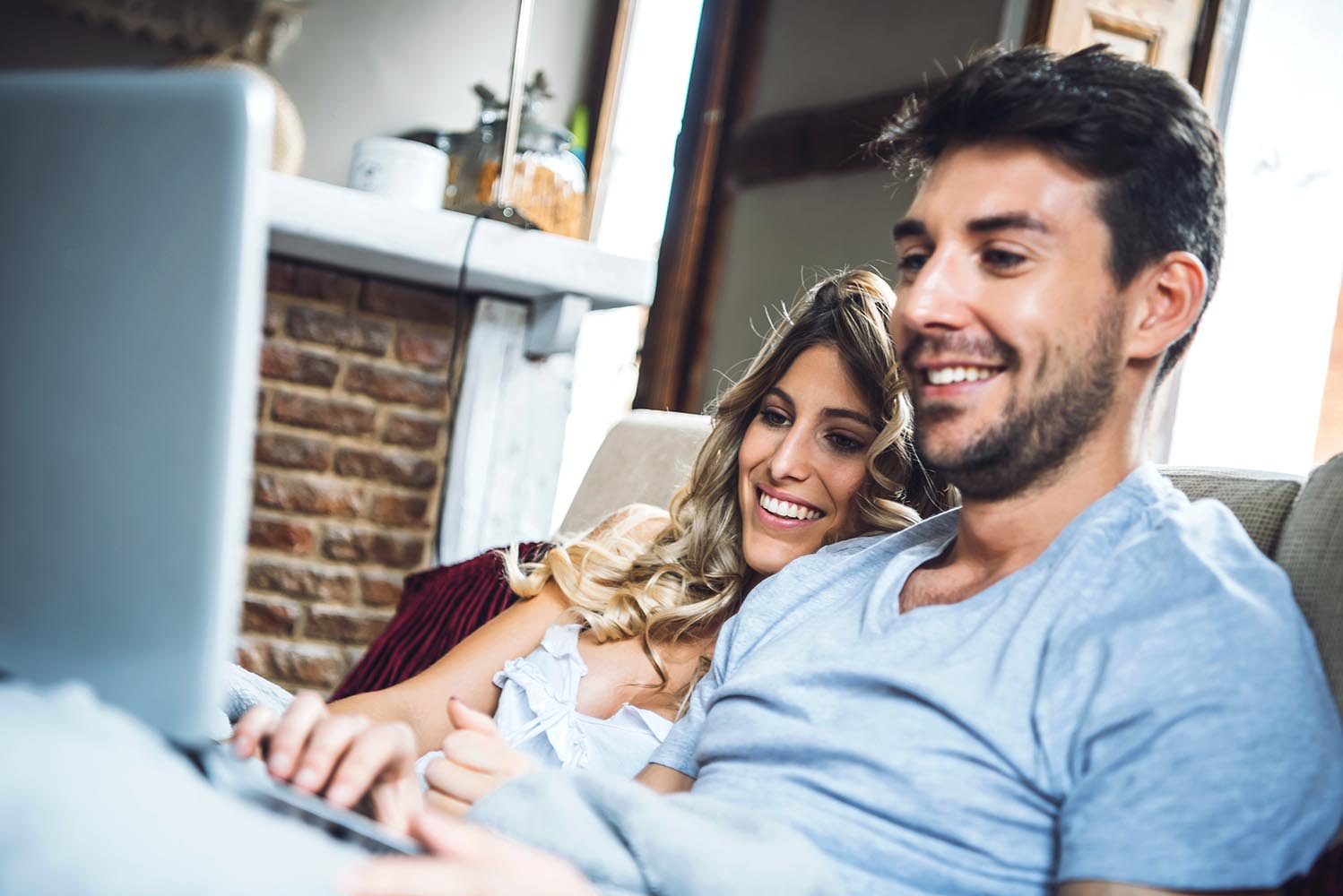 Merry couple on sofa with laptop