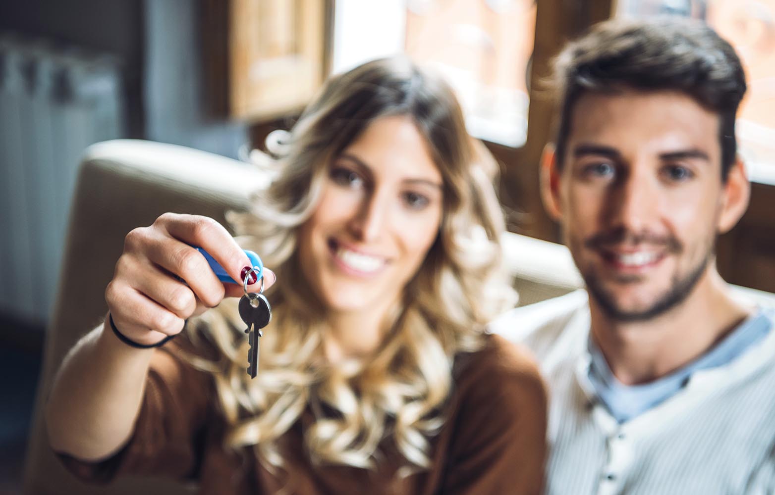 Cheerful couple holding keys from new apartment