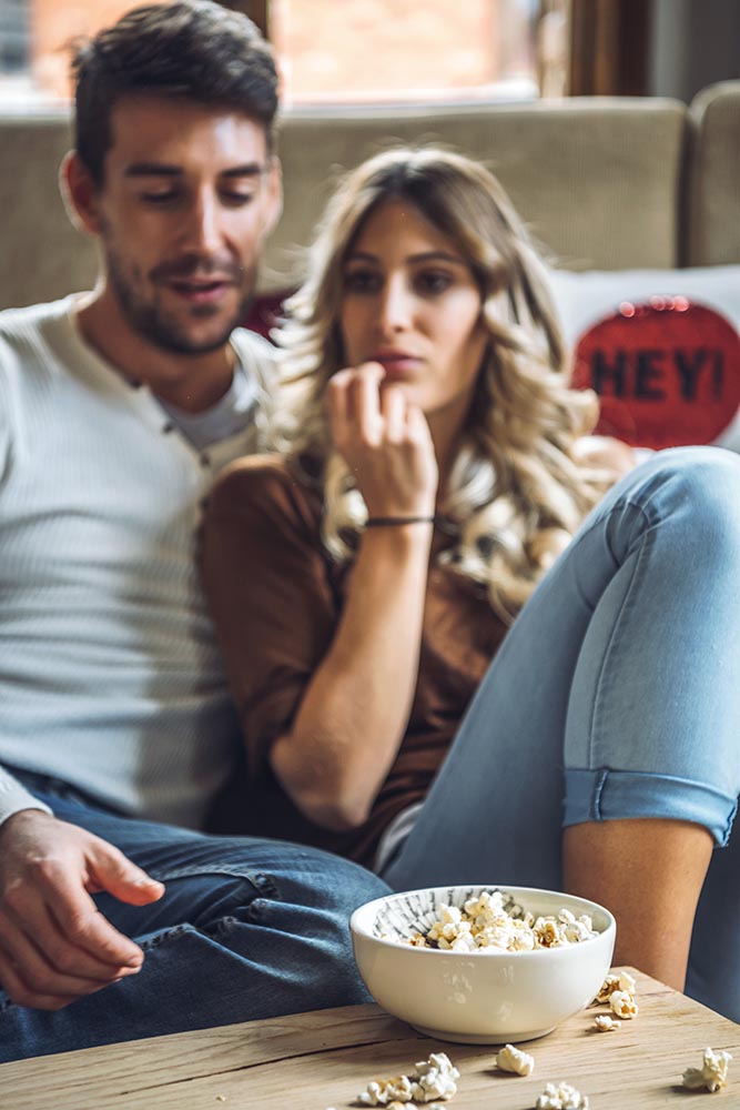 Loving couple enjoying popcorn and movie