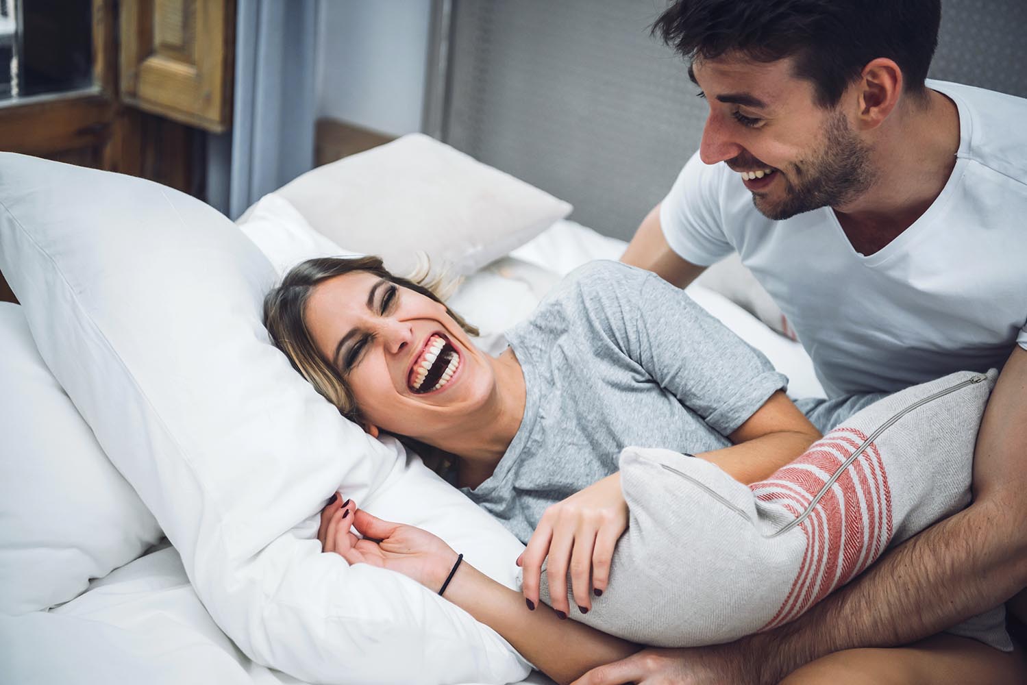 Couple laughing while playing in bed