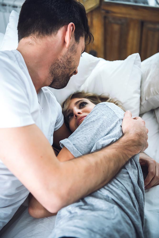 Male embracing woman in bed