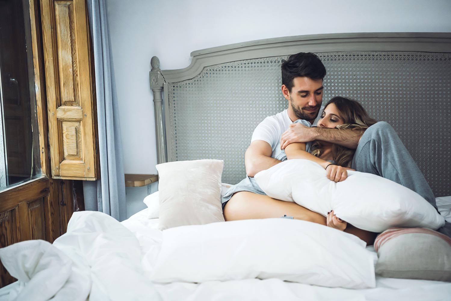 Cheerful couple embracing in bed
