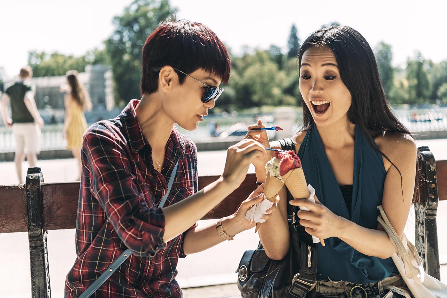 Asian women eating ice cream on park bench