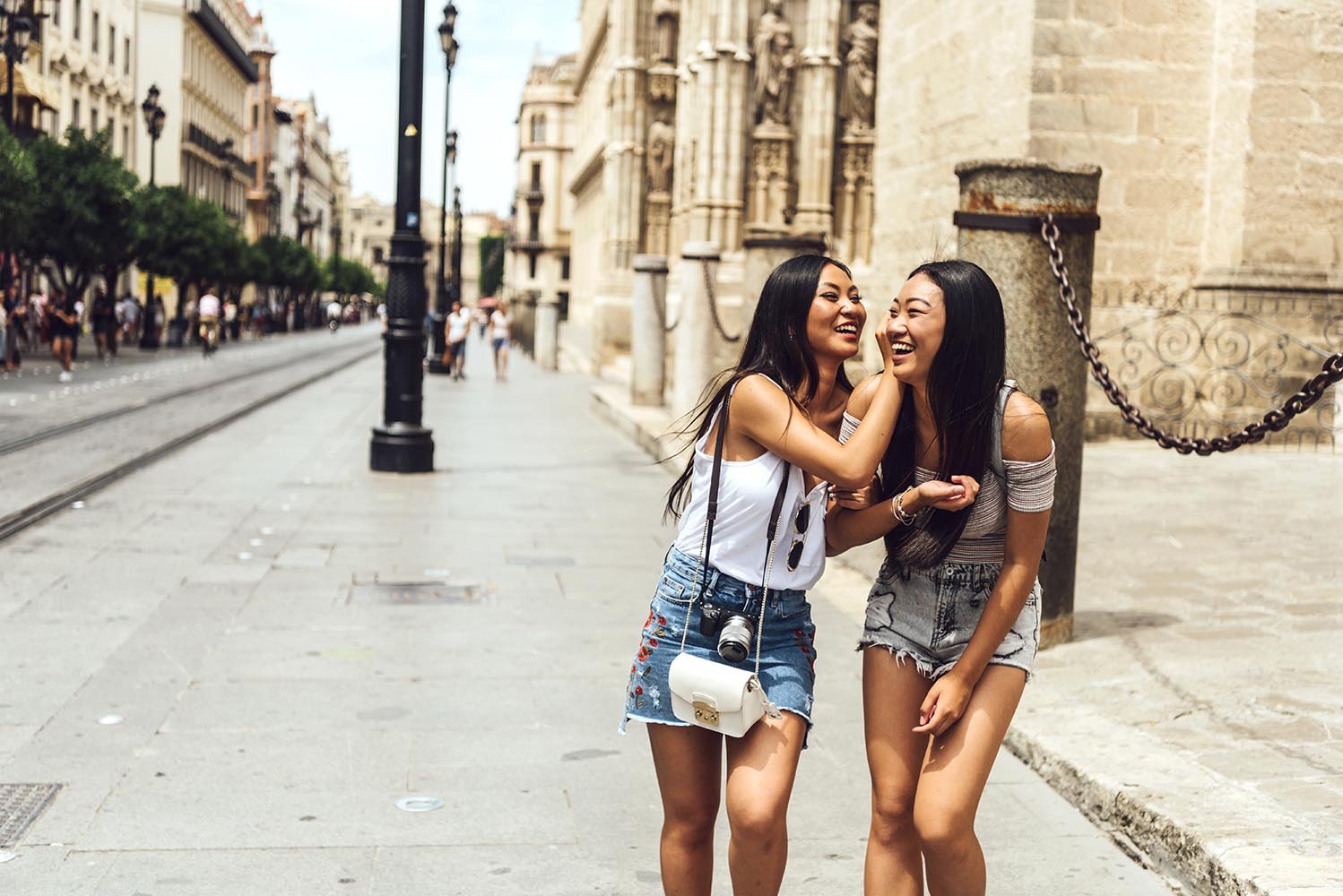 Two Chinese girls walking on street hugging