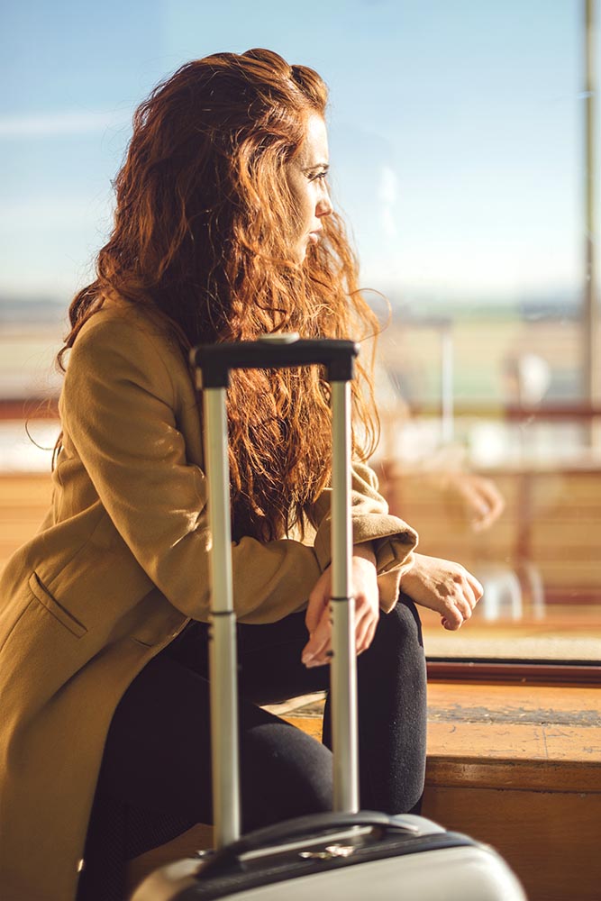 Woman with suitcase sitting in airport