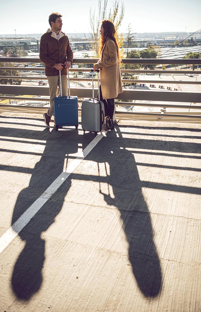 Couple with suitcases standing at handrail