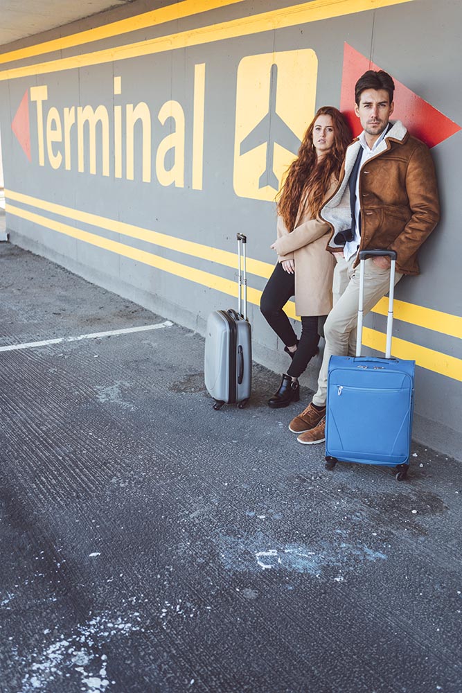 Couple with suitcases leaning on terminal wall