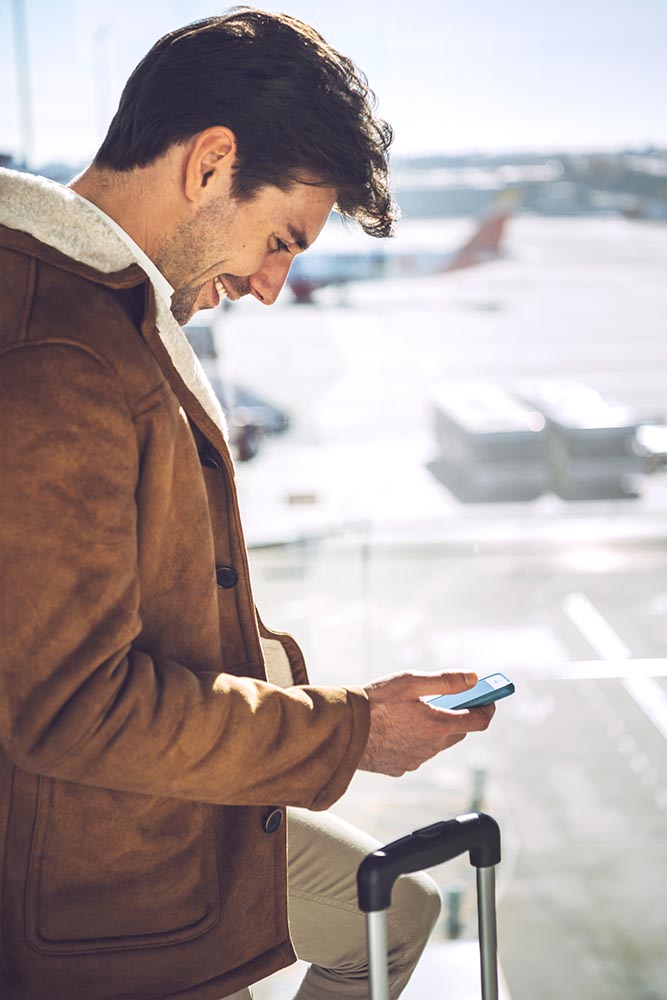 Cheerful man with smartphone in airport