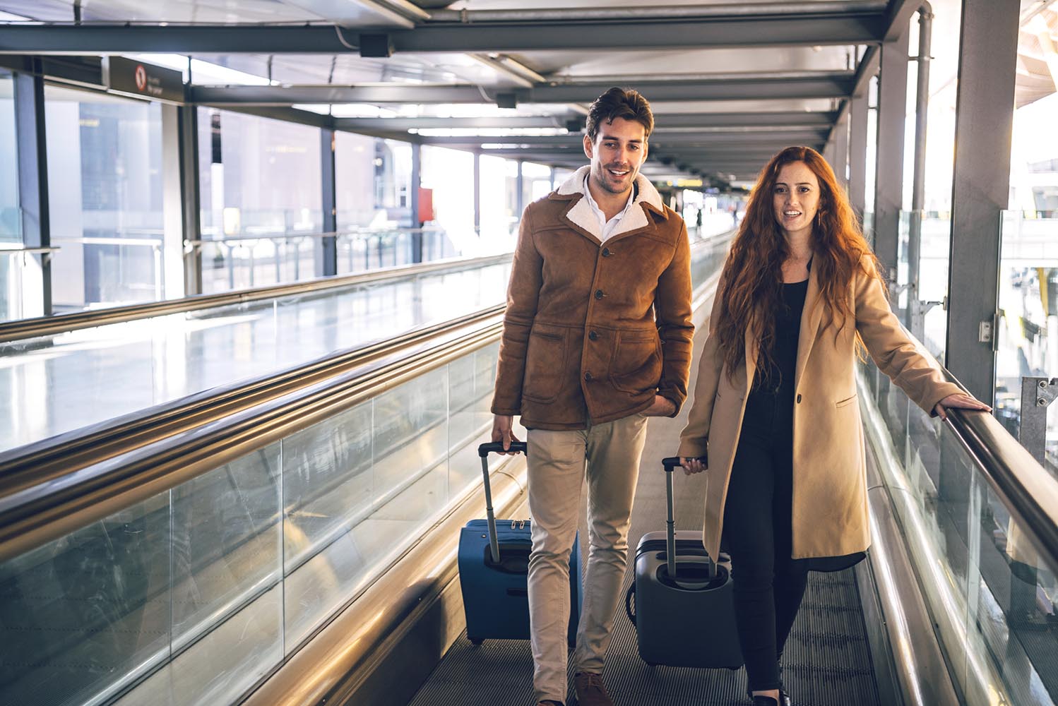 Cheerful couple with luggage on travelator