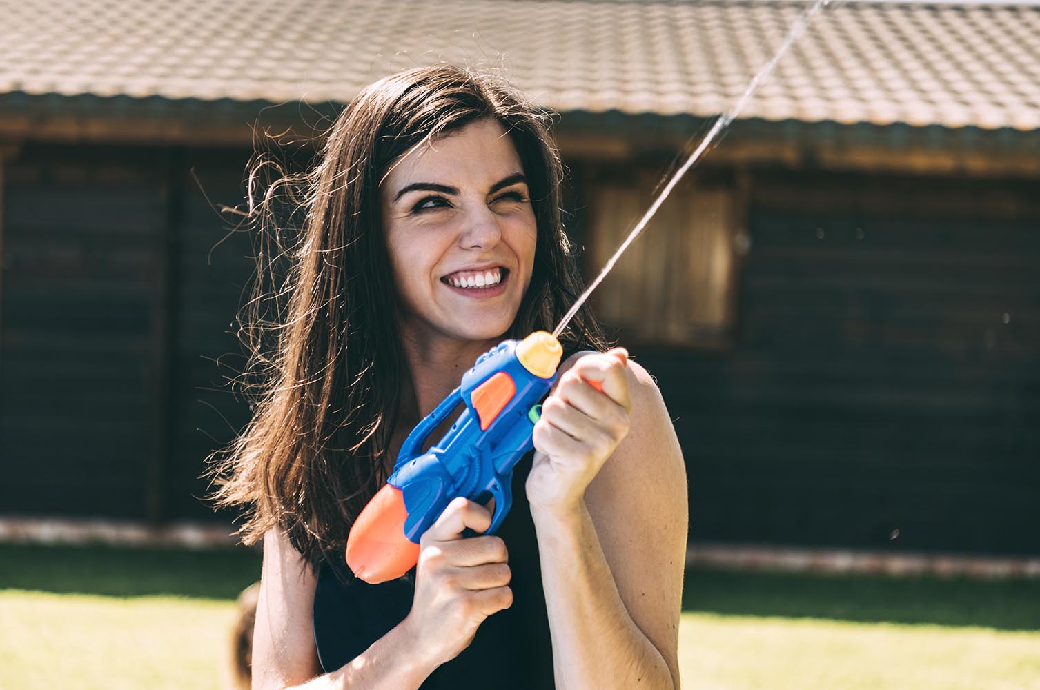 Young woman shooting and splashing with water gun