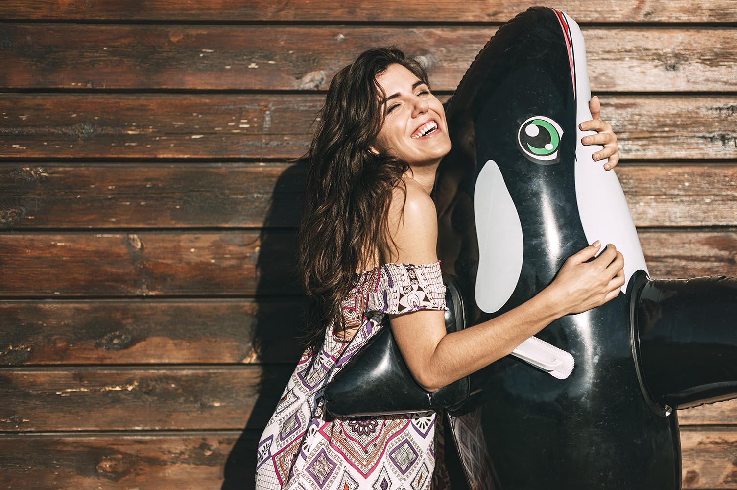 Beautiful young girl hugging an inflatable orca whale