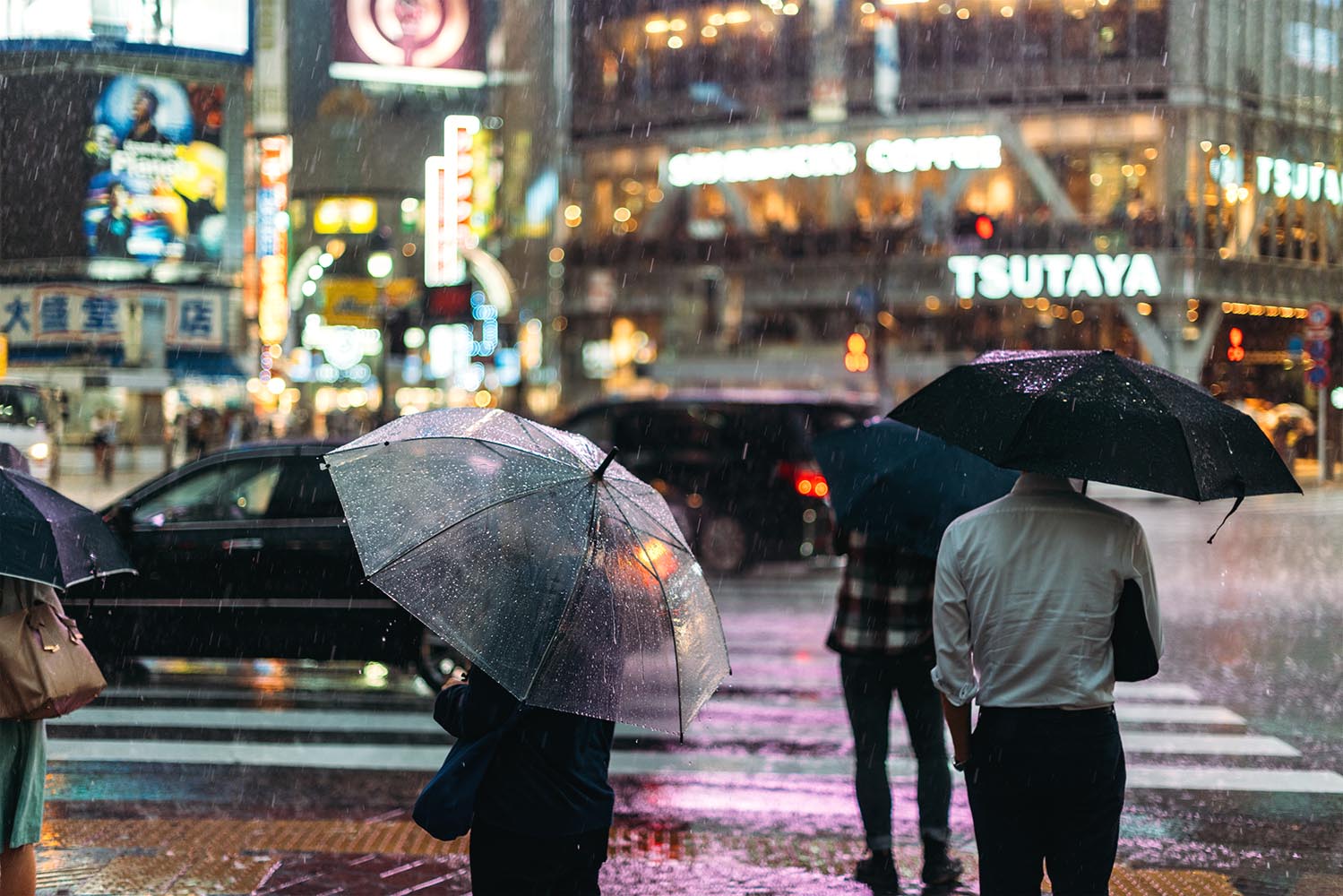 Shibuya, people crossing the street under the rain at night. Tok