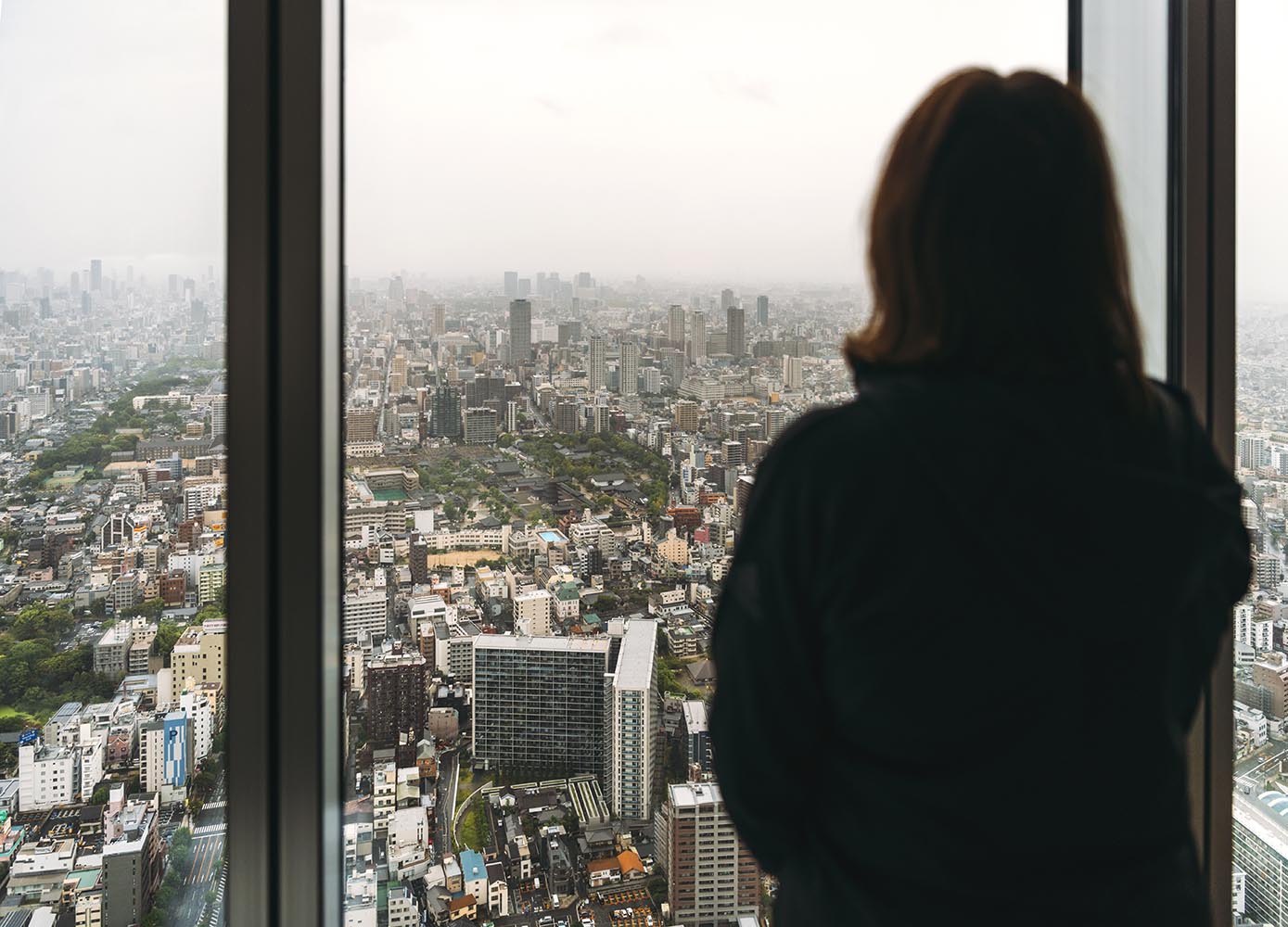 woman looking out the window in a skycrapper in Osaka city, Japa